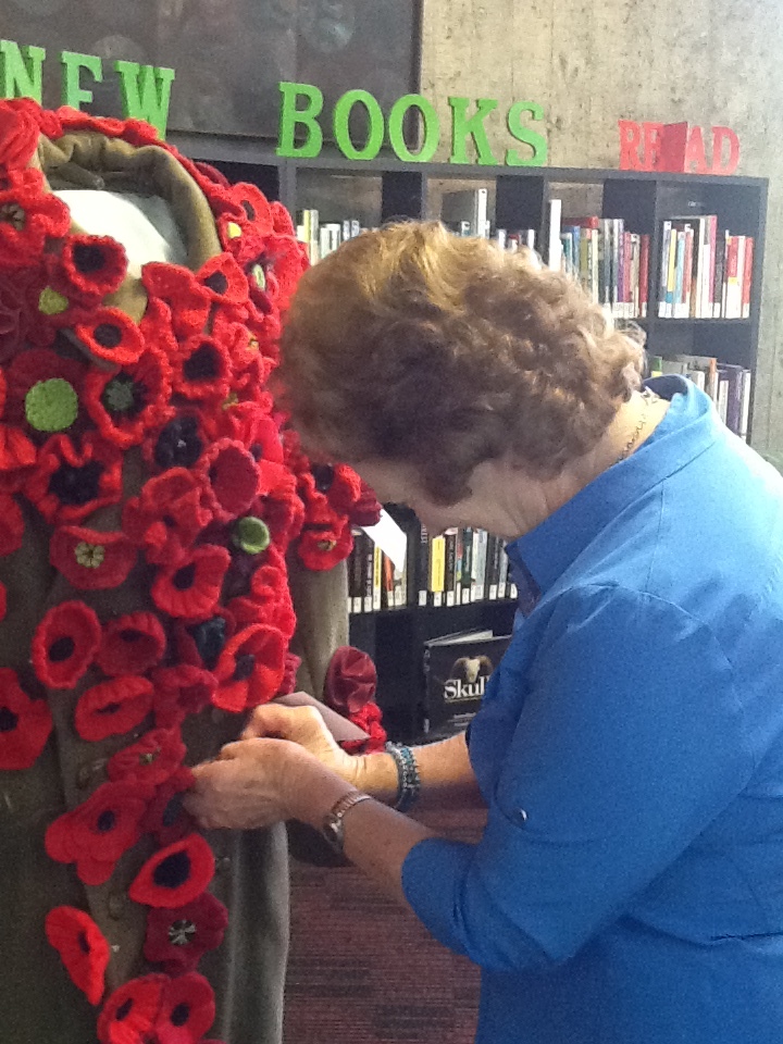 Aoraki Embroiderers' Guild member pinning a poppy on a uniform