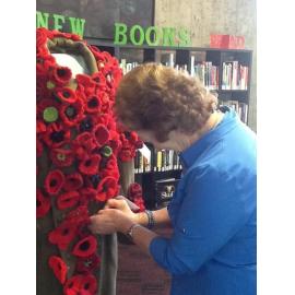 Aoraki Embroiderers' Guild member pinning a poppy on a uniform