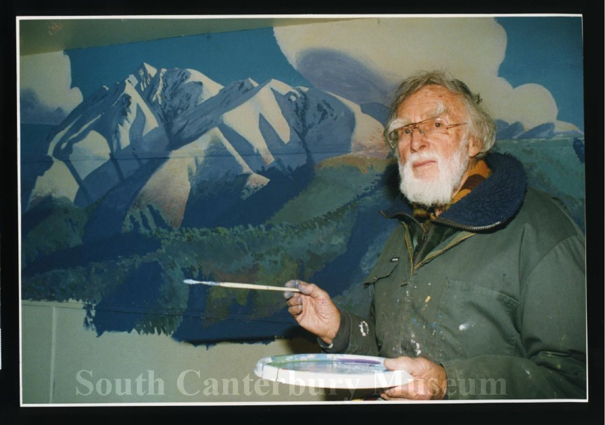 Artist Austen Deans with his mural painted in the Peel Forest Hall, 20 August 1993.
Image courtesy of the South Canterbury Museum, item 2012/186.2362. Please contact the museum for more information.