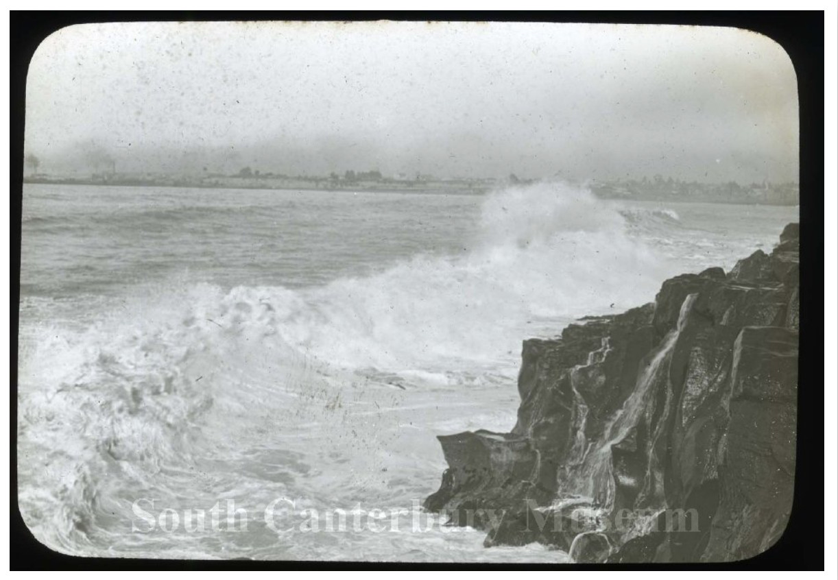 Dashing Rocks, Waves crashing on the point of Dashing Rocks with Timaru in the background, circa 1915.
Image courtesy of the South Canterbury Museum, item 979/56.003. Please contact the museum for more information.


